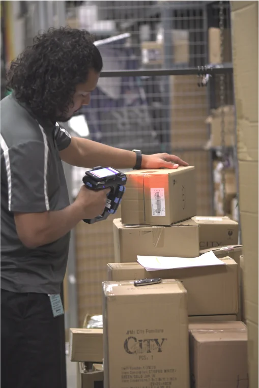Retail associate scanning a City Furniture carton during a showroom inventory count