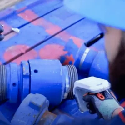 Field technician using a handheld device near industrial equipment