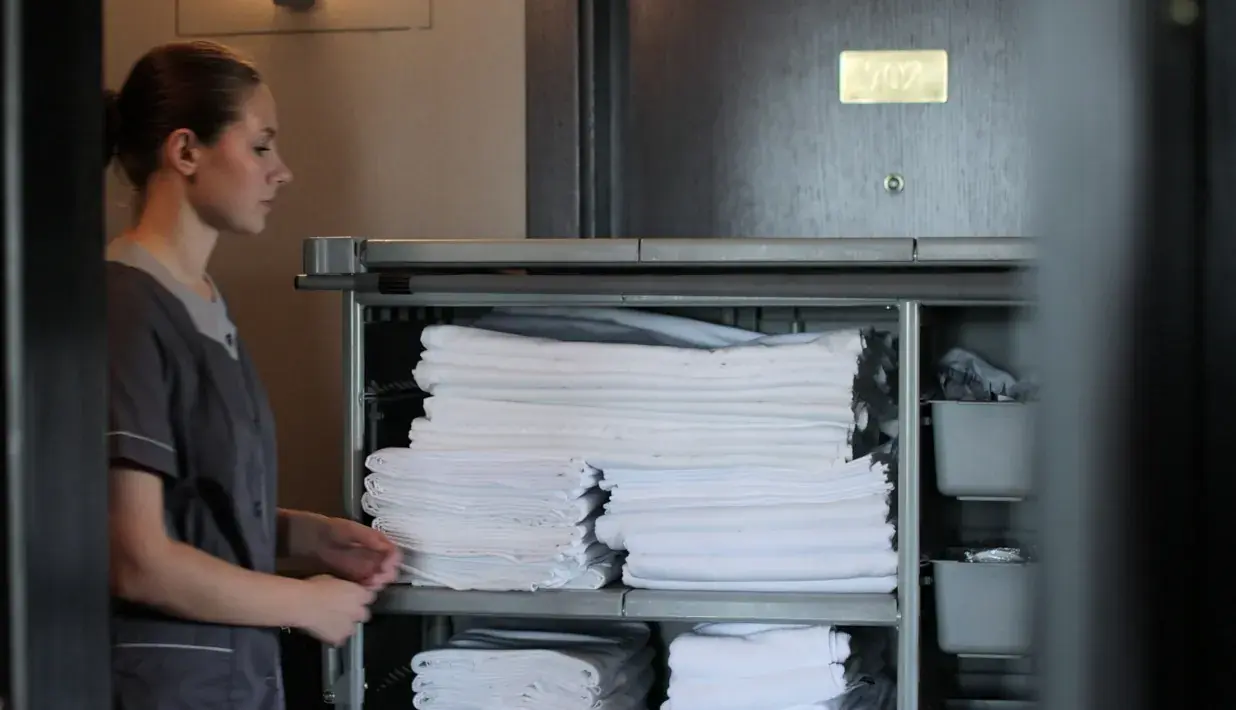 Hospitality worker organizing folded linen on a service cart