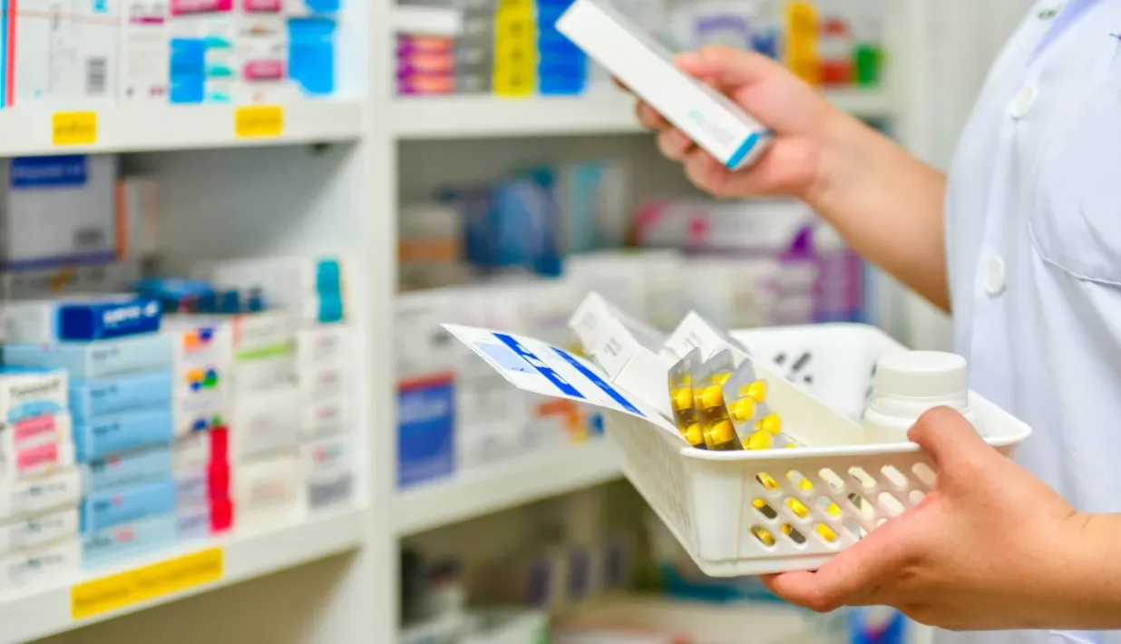 Healthcare worker handling medicine packs beside a storage cabinet