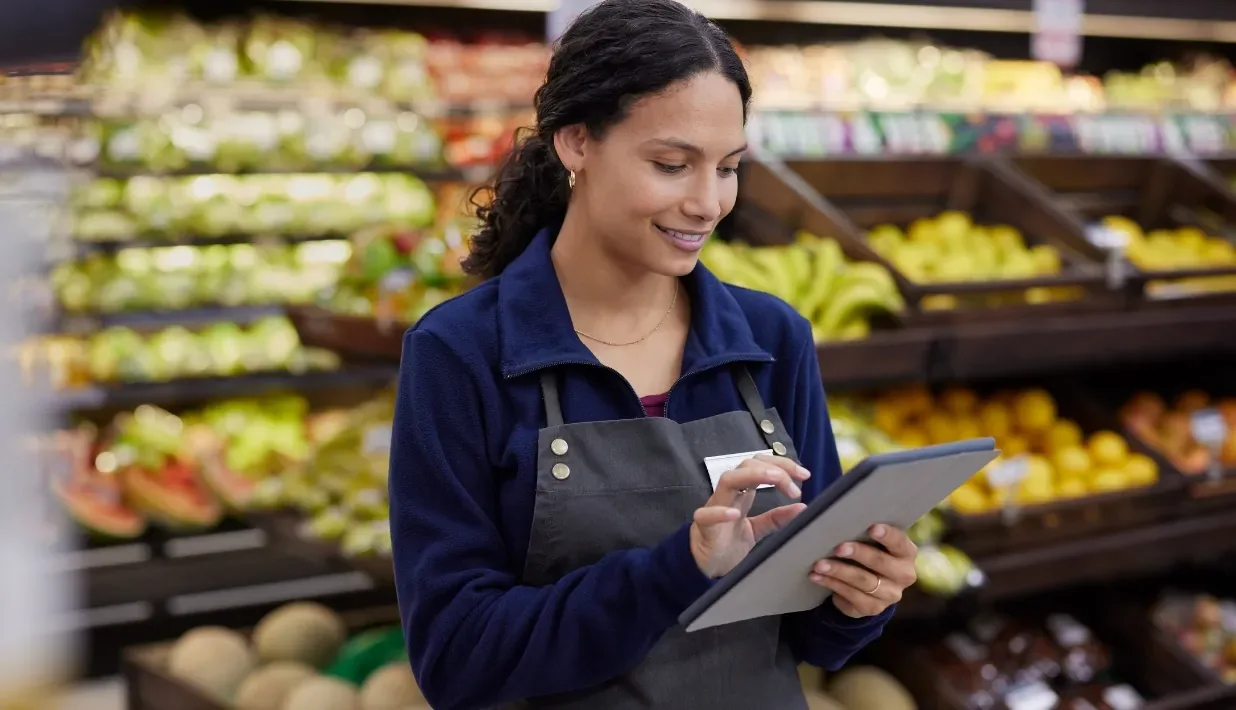 Retail team member checking produce inventory with a tablet